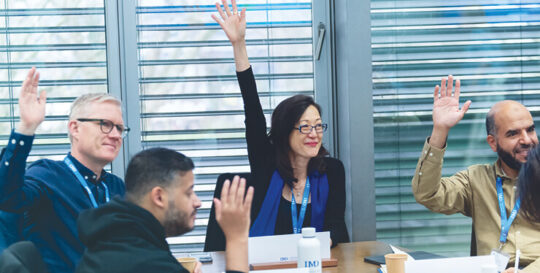 Open program participants raising their hands on class - IMD Business School